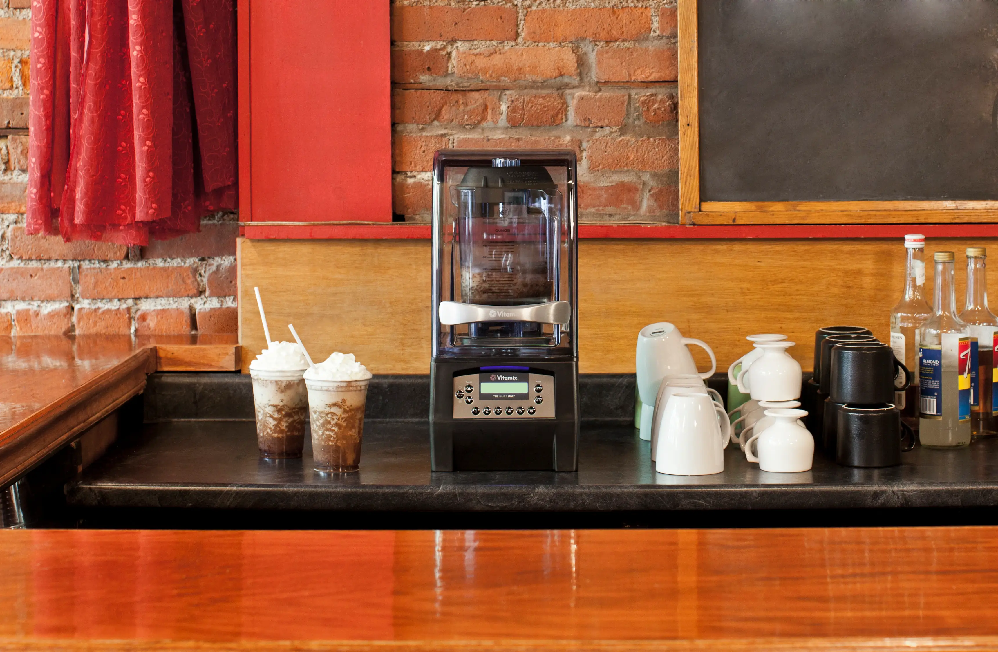 VitaMix Mixer auf Theke mit Tassen und Getränken