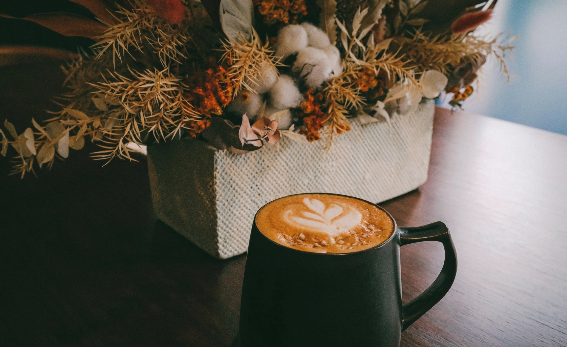 Kaffeetasse mit Latte Art vor herbstlicher Dekoration