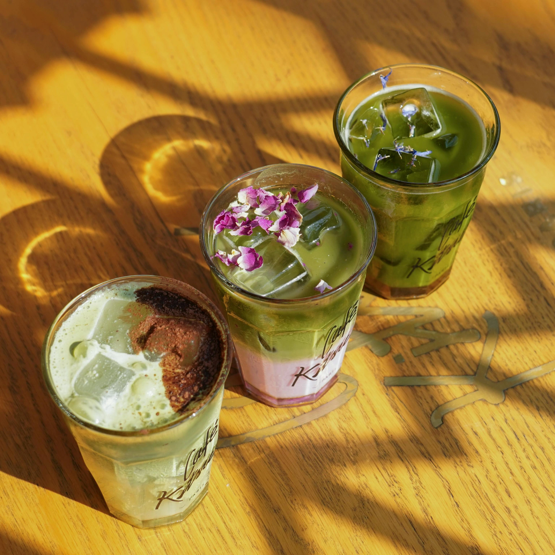 drei verschiedene Iced Matcha Getränke mit Eiswürfeln und Blüten